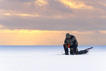Lonely fisherman at winter fishing. Ice fishing in the north of Scandinavia sunset