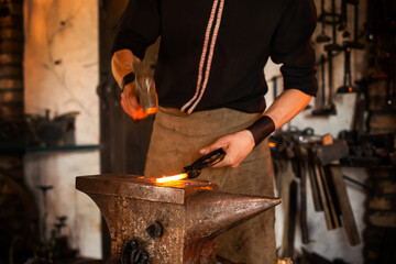 Blacksmith handles the molten metal, caucasian blacksmith working with open fire in furnace. The...