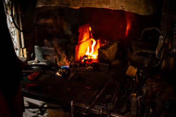 Professional blacksmith working with metal quenching hot iron part with water at forge. Handmade,...