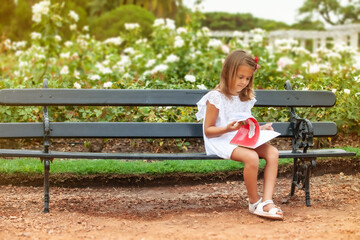 little girl with a book in her hands in the park outdoors