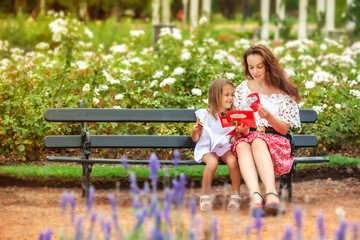 mother with daughter reading children's book in the park