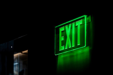 Exit sign in green neon color on black background with copy space
