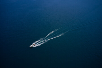 The yacht is moving fast on blue water. Top view of the boat. Aerial view luxury motor boat. Top view of a white boat sailing in the blue sea.