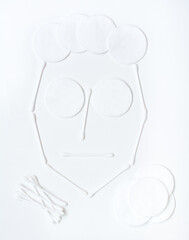 Female face made of cotton pads and cotton swabs on a white background. Facial skin care concept. Top view