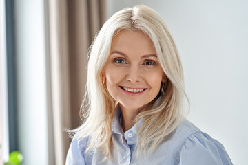 Smiling sophisticated 50s middle aged blond business woman looking at camera. Happy mature elegant...