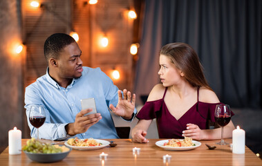 Annoyed Woman Arguing With Boyfriend In Restaurant, Blaming Him For Smartphone Addiction