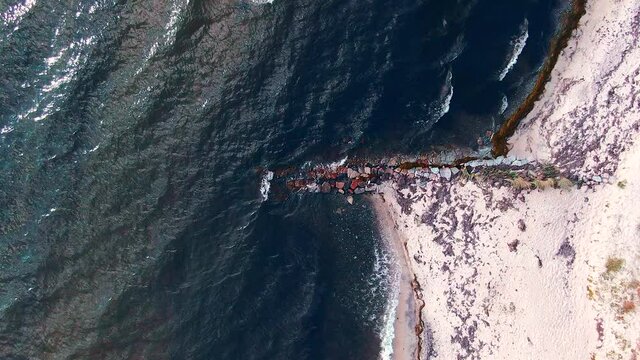 Steady drone shot of small waves hitting the beach at the baltic coast in Denmark. 