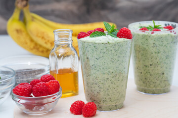Celery spinach banana smoothie with Chia seeds, honey, fresh raspberries and mint leaves close up. Green detox smoothie, healthy food, breakfast