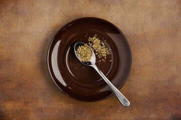 Metal spool with seasoning on a brown plate shot from above