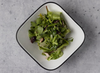 Healthy salad in a white bowl on a concrete counter