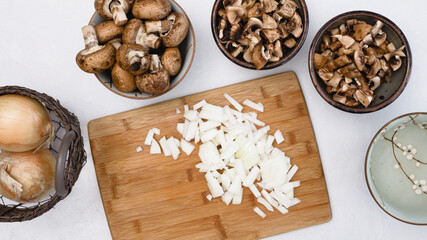 Fresh raw chopped onion close up on wooden board on kitchen table, flat lay
