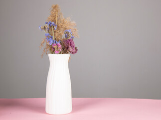 dried flowers in vase on the pink table