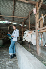 a vet smiles at the camera wearing a notepad using a clipboard in a cattle ranch pen