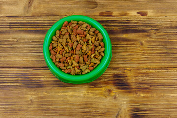 Obraz na płótnie Canvas Dry food for cat or dog in bowl on wooden background. Pet food on wood surface