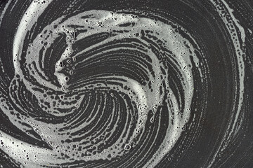Background of a dark plate on which soapy water is blurred and bubbles. A spiral in the middle