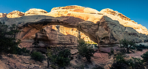 Fototapeta na wymiar Wide shot of sandstone arch with last sun rays in Capitol Reef national park in Utah, america