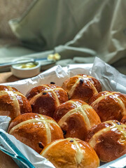 Homemade Hot Cross Buns. A spiced sweet bun made with fruit, marked with a cross on the top. Traditionally eaten on Good Friday in the United Kingdom. Knife with butter for tasting