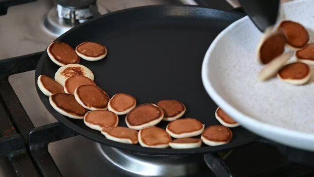 Cooking tiny mini pancake cereal - trendy quarantine food. Ready-made pancakes are collected in a plate for breakfast. 4k video