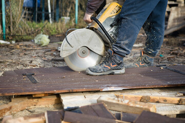 A worker cuts the wood with a petrol saw