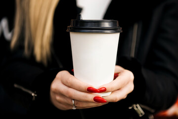 Hands  hold paper cup with coffee or tea. Takeaway food concept on blue background and copy space.
