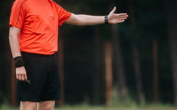 Soccer referee blowing whistle and pointing.