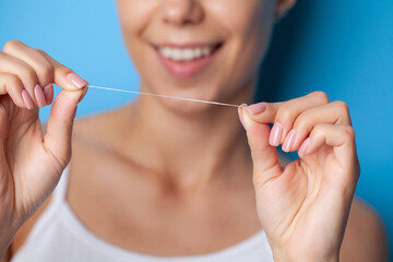 Cheerful brunette woman using dental floss in bathroom