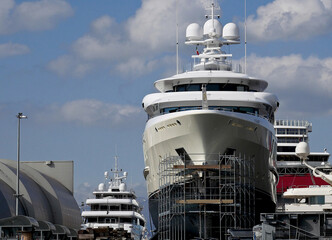 Luxury yachts in a shipyard with scaffolding on the hull - 415654876