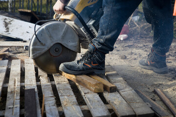 A worker cuts the wood with a petrol saw