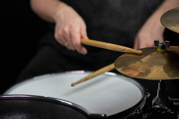 Professional drum set closeup. Man drummer with drumsticks playing drums and cymbals, on the live music rock concert or in recording studio   