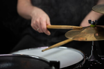 Professional drum set closeup. Man drummer with drumsticks playing drums and cymbals, on the live music rock concert or in recording studio   