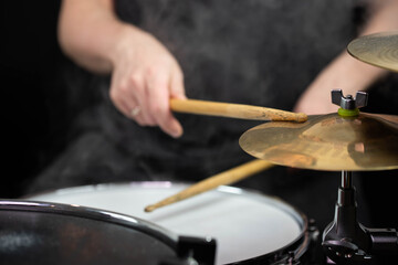 Professional drum set closeup. Man drummer with drumsticks playing drums and cymbals, on the live music rock concert or in recording studio   
