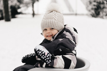 Cute cute boy in a sled in the snow, active lifestyle, winter, family