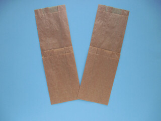 Letter V from four brown gift bags on a light blue background. 