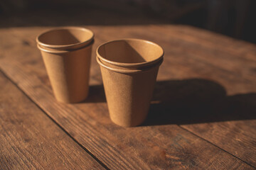 disposable dark brown kraft paper cups stand on wooden table