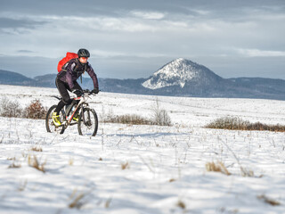 Mountain biker in snowy landscape. Sportsman ridding in snow, heavy terrain