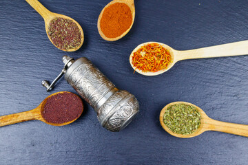Set of different aromatic spices and spice mill on black slate. Top view