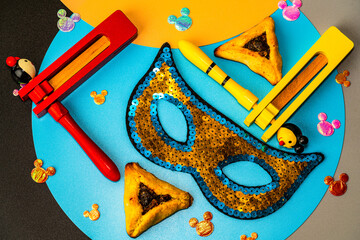 Purim celebration concept. Ratchet, hamantaschen cookies and masquerade mask
