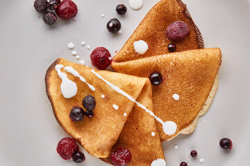 Close-up of thin pancakes with berries on a plate. Russian traditional pancakes. East Slavic traditional holiday Maslenitsa.