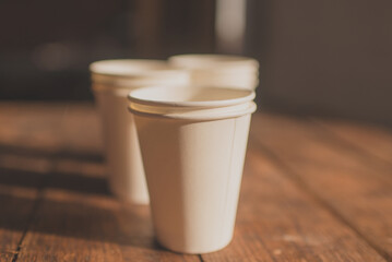 disposable cups made of white kraft paper stand on a wooden table