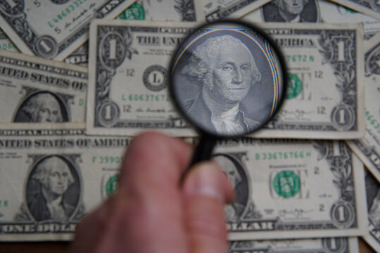 Through the magnifying glass of the dollar is a portrait of late American President George Washington. Bank image and commercial photo, paper money background.
