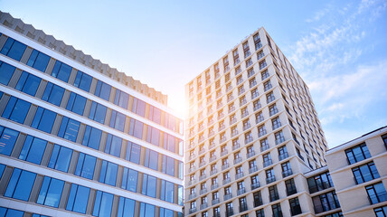 Naklejka premium Downtown corporate business district architecture. Glass reflective office buildings against blue sky and sun light. Economy, finances, business activity concept. Rising sun on the horizon.