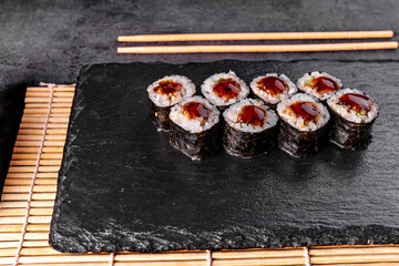 Maki Sushi Rolls with eel on black stone on dark background. Sushi menu. Japanese food. Closeup of delicious japanese food with sushi roll. Horizontal photo