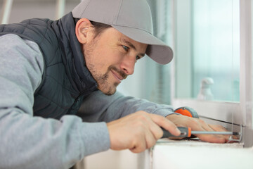 Naklejka na ściany i meble male repairman fixing window with screwdriver