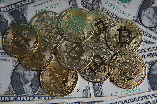 Pile of US dollar cash. Next to it are a number of gold bitcoins and a silver digital cryptocurrency coin. Bank image and commercial photo background. 