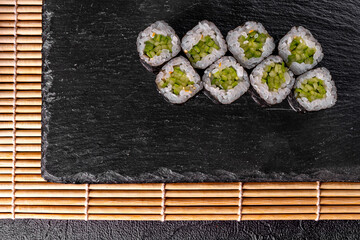 classic Maki roll with cucumber on a black mirror background