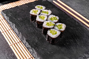 classic Maki roll with cucumber on a black mirror background