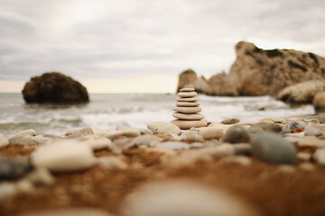 Pyramid stones on the seashore on a sunny day on the blue sea background. Happy holidays. Pebble beach, calm sea, travel destination. Concept of happy vacation on the sea.