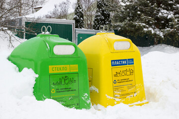 Green and yellow containers for separate waste collection for glass and plastic. Boxes for separate collection of garbage in winter.