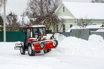 A old tractor clears the street of snow. Street cleaning in winter. An automated snow removal