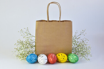 Painted eggs and flowers lie next to a paper bag. Delivery on Easter. A copy of the space....